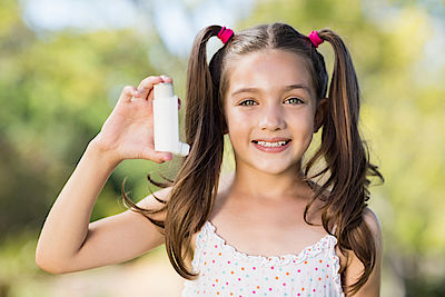 Girl holding an asthma inhaler in the park
