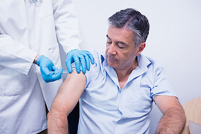 Doctor giving injection to his patient at the hospital